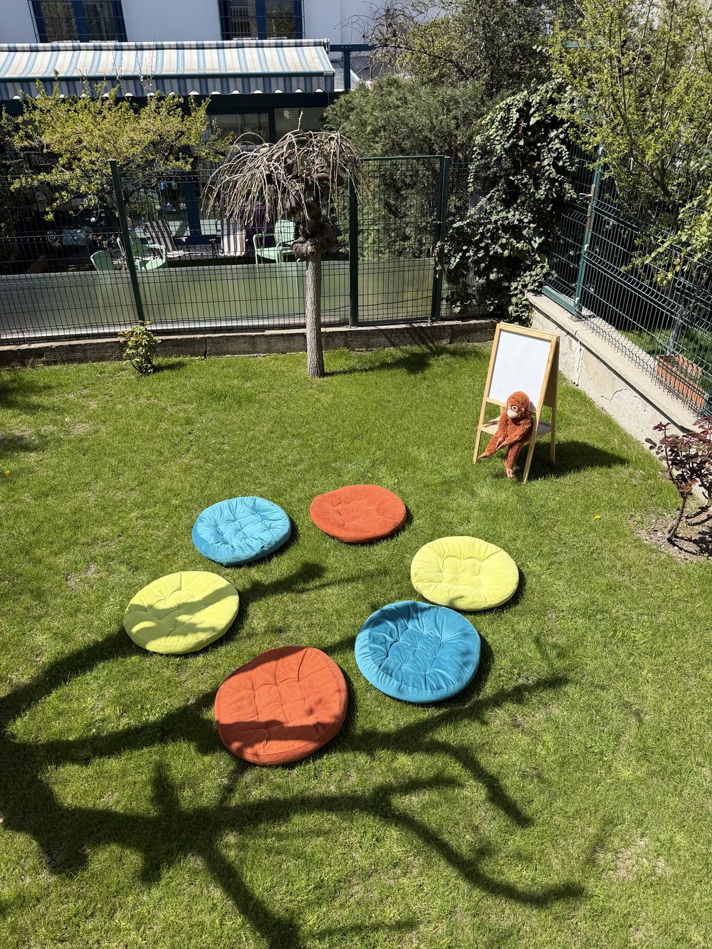 Bahçede çimenlerin üzerine dizilmiş renkli oturma minderleri